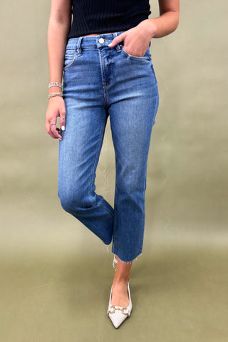 Person wearing blue jeans and a black top on a beige background
