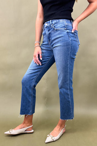 Person wearing blue jeans and white shoes on a beige background
