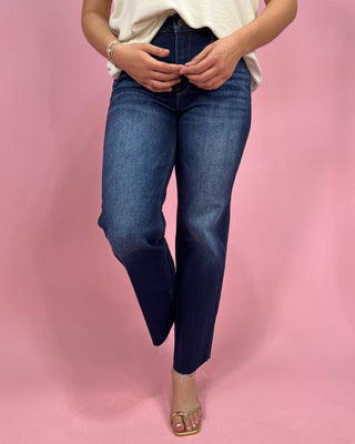 Person wearing blue jeans on a pink background