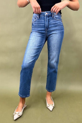Person wearing blue jeans and white shoes on a green background