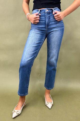 Person wearing blue jeans and white shoes on a green background