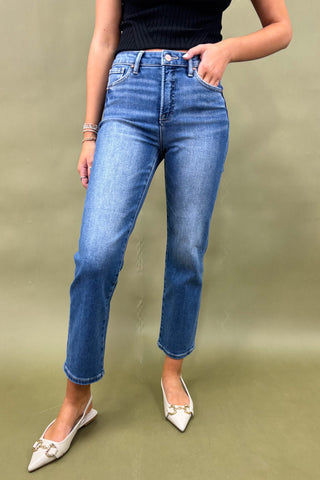 Person wearing blue jeans and white shoes on a green background