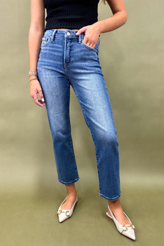 Person wearing blue jeans and white shoes on a green background
