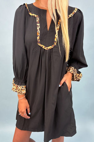Black dress with leopard print details on a plain background