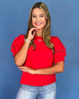 Woman wearing a red blouse with puff sleeves against a blue background