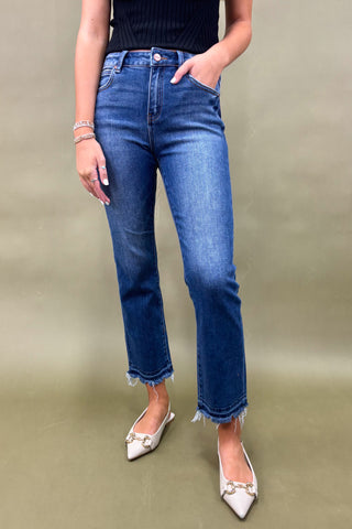 Person wearing blue jeans and white shoes on a plain background
