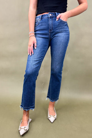 Person wearing blue jeans and white shoes on a plain background
