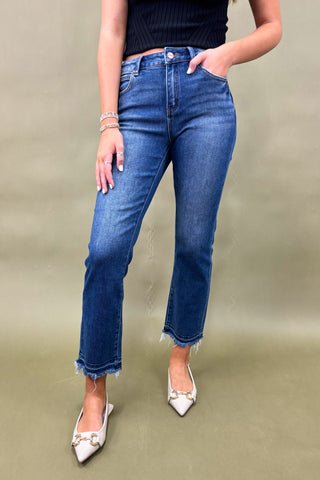 Person wearing blue jeans and white shoes on a plain background