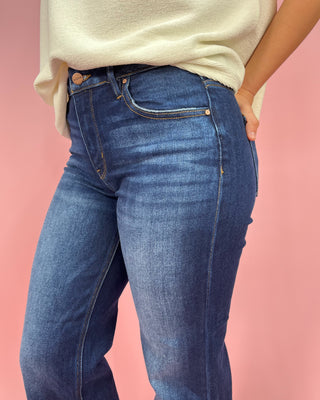 Person wearing blue jeans and a beige top on a pink background