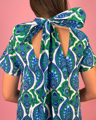 Woman wearing a blue and green patterned dress with a pink background