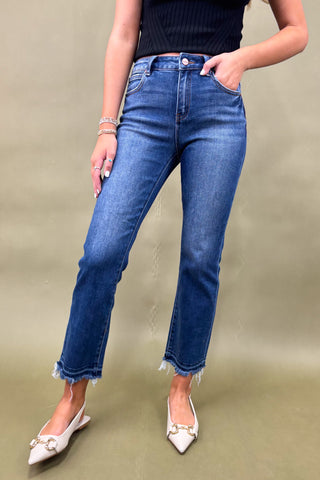 Person wearing blue jeans and white shoes on a beige background