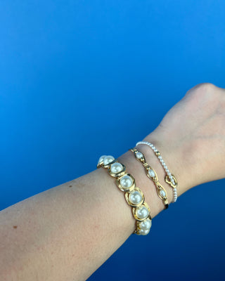 Shop the Pearl Bracelet featuring elegant white faux pearls in polished gold-tone settings with a comfortable stretch fit for timeless style.