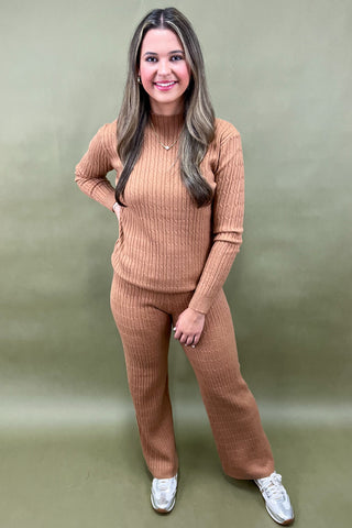 Woman wearing a brown ribbed sweater and pants set on a green background