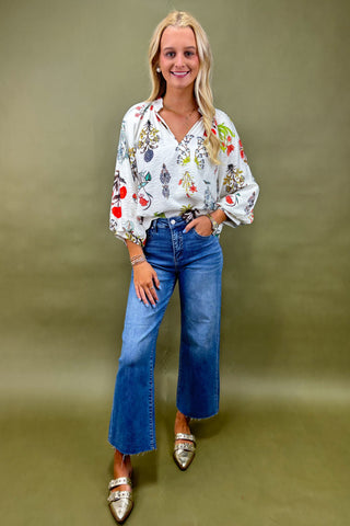 Woman wearing a floral blouse and blue jeans against a green background