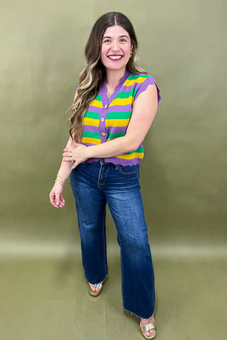 Woman wearing a colorful striped shirt and blue jeans against a green background