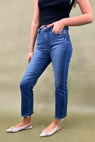 Person wearing blue jeans and a black top on a beige background