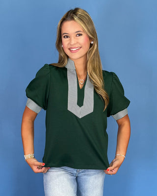 Woman wearing a green blouse with striped sleeves against a blue background