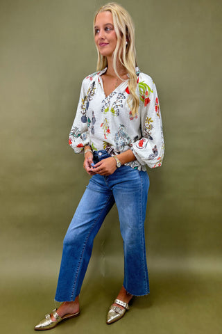 Woman wearing a floral blouse and blue jeans against a green background