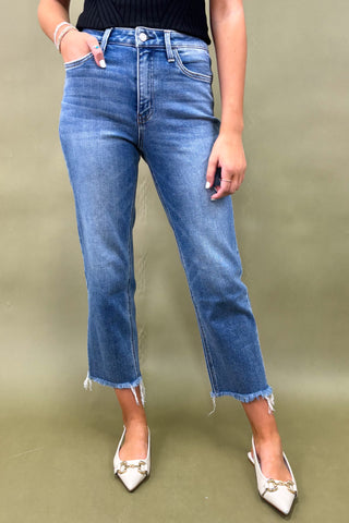 Person wearing blue jeans and white shoes on a green background