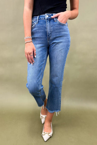 Person wearing blue jeans and white shoes on a plain background