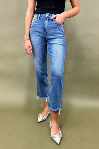 Person wearing blue jeans and white shoes on a plain background