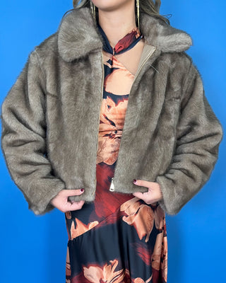 Taupe faux fur cropped jacket with plush texture, oversized collar, long sleeves, and front zipper closure.