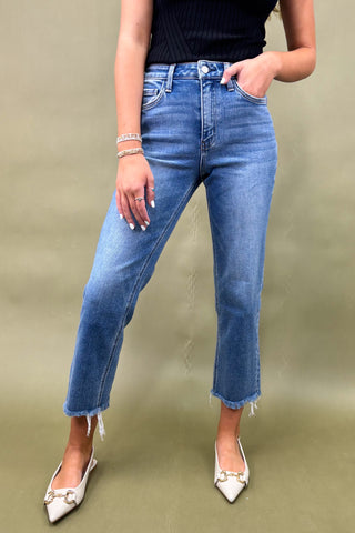 Person wearing blue jeans and white shoes on a plain background