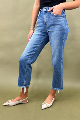 Person wearing blue jeans and white shoes on a green background