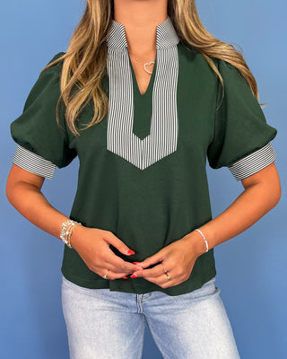 Woman wearing a green blouse with striped collar against a blue background