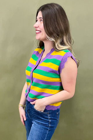 Woman wearing a colorful striped sweater vest against a green background