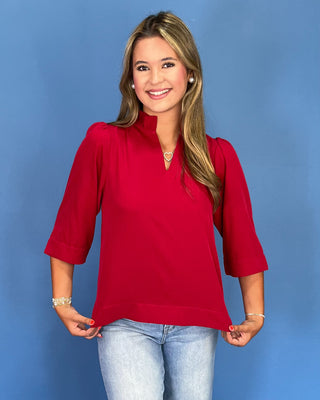 Woman wearing a red top and blue jeans against a blue background