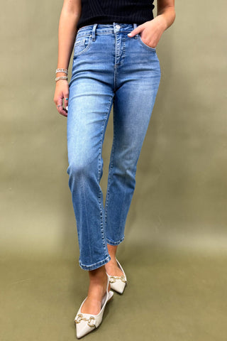 Person wearing blue jeans and white shoes on a plain background