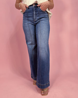 Person wearing blue jeans on a pink background