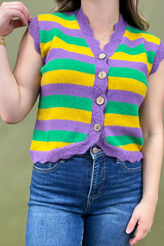 Person wearing a colorful striped cardigan with a green background