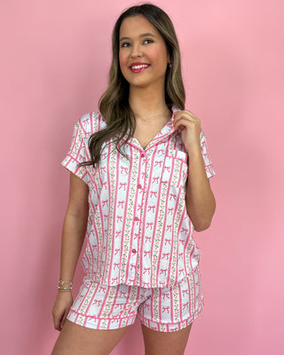 Woman wearing a pink and white patterned pajama set against a pink background