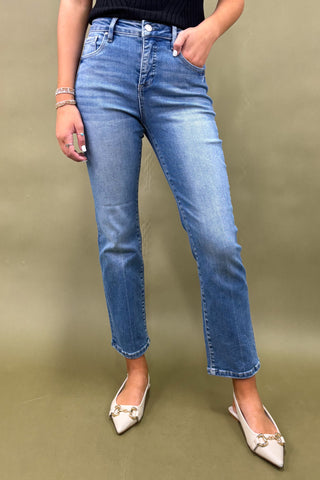 Person wearing blue jeans and white shoes on a green background