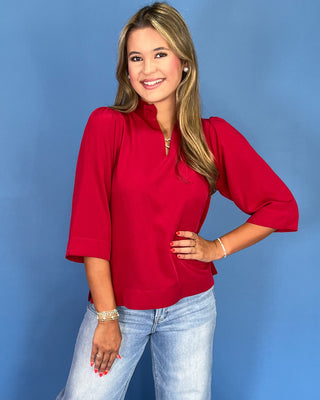 Woman wearing a red blouse and blue jeans against a blue background