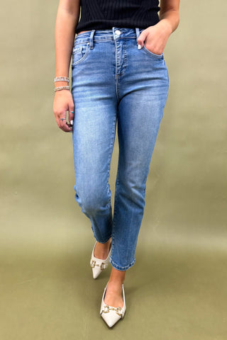 Person wearing blue jeans and white shoes on a plain background