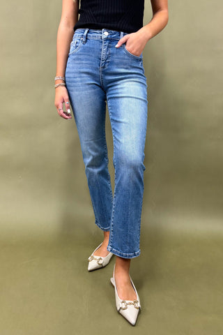 Person wearing blue jeans and white shoes on a green background