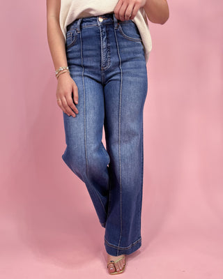 Person wearing blue jeans on a pink background
