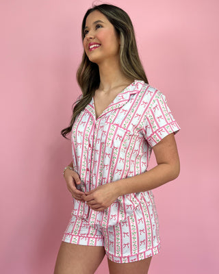 Woman wearing a pink and white patterned pajama set against a pink background