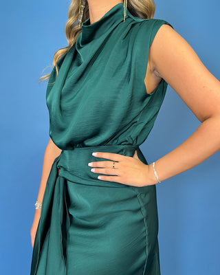 Emerald green satin midi dress with a draped cowl neckline, sleeveless design, and flattering tie-waist detail.