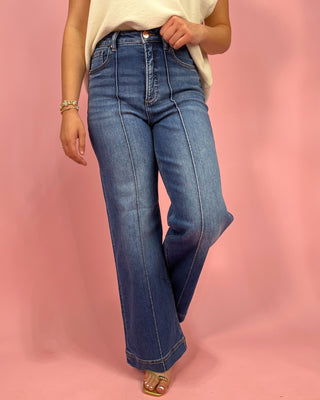 Person wearing blue jeans on a pink background