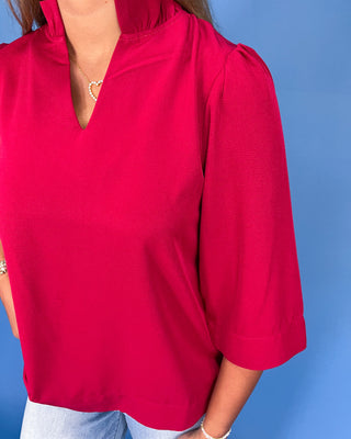 Person wearing a bright pink blouse against a blue background