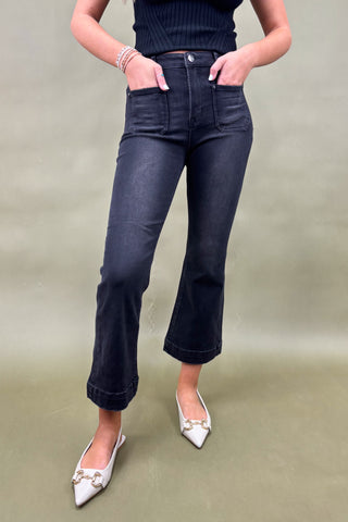 Person wearing black jeans and white shoes on a plain background