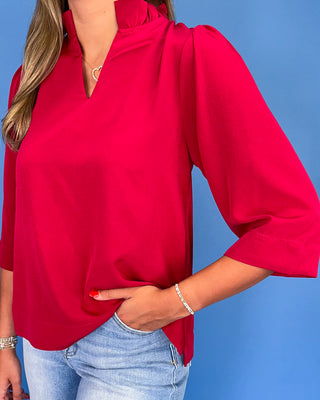 Red blouse worn by a person against a blue background