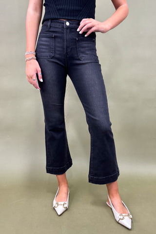 Person wearing black jeans and white shoes on a plain background