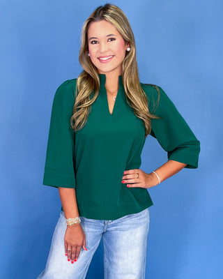 Woman wearing a green blouse and blue jeans against a blue background