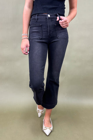 Person wearing black jeans and a dark top on a plain background