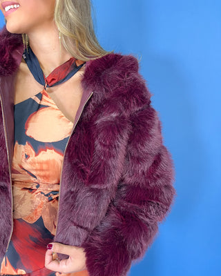 Burgundy faux fur cropped jacket with plush textured fabric, oversized collar, long sleeves, and gold zipper closure.